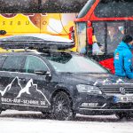 Auto mit Skibox im Schneefall
