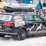 Auto mit Skibox im Schneefall von hinten