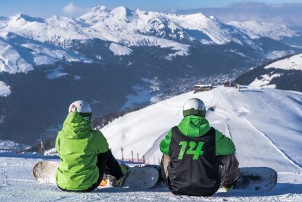 Zwei Snowboarder schauen auf die sonnige Piste