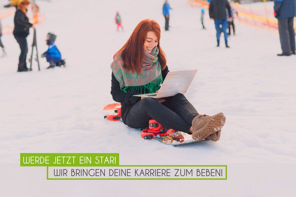 Frau sitzt auf dem Schnee mit Laptop